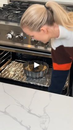 a woman bending over in front of an oven