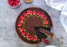 a chocolate tart with raspberries on top and one slice missing from it