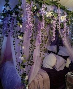 a canopy bed covered in purple flowers and greenery