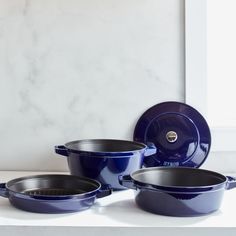 blue pots and pans sitting on top of a white counter next to a window