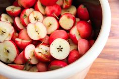 a bowl filled with red apples on top of a wooden table