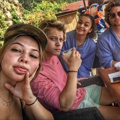 a group of people sitting around each other at a table eating food and drinking beverages