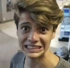 a young man making a face while standing next to a parking meter