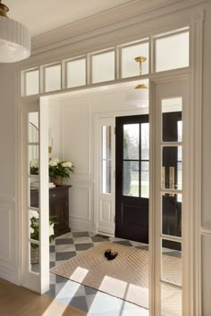 an open door leading into a room with checkered flooring and black glass doors