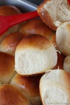 bread rolls with butter on them sitting in a red bowl, ready to be baked