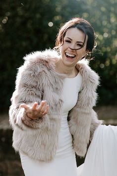 a woman in a white dress and fur coat