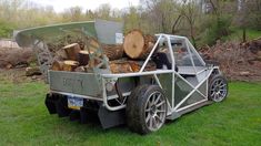 a truck with logs in the back is parked on grass