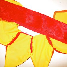 a red and yellow scarf laying on top of a white table next to a pair of scissors