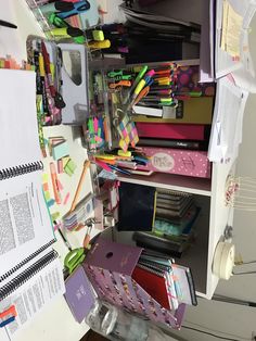 a cluttered desk with lots of papers and pens on the top shelf next to it