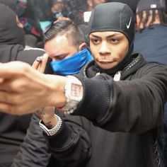 a man in a black hoodie is holding his hand out to another person wearing a blue face mask