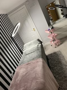 a bedroom with black and white stripes on the walls, a pink bed in front of a mirror