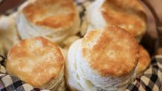 several biscuits are in a basket on a checkered cloth with a wooden bowl behind it