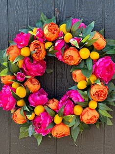 a wreath with oranges and pink flowers on it