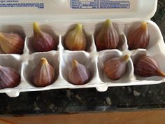 an egg carton filled with nine different types of figs on a counter top