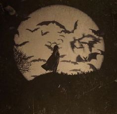 a woman standing in front of a full moon with bats flying over her head and on the ground