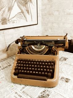 an old fashioned typewriter sitting on top of a table next to a framed drawing