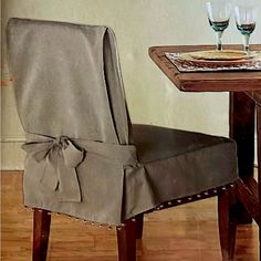 a dining room chair with a bow on the back and two wine glasses next to it