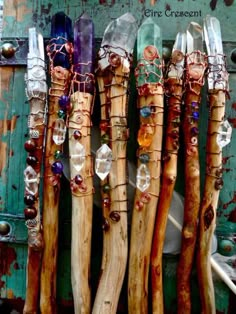 several wooden sticks are lined up against a green door with glass beads and chains hanging from them