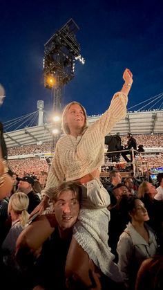 a woman is sitting on the shoulders of a man at a concert