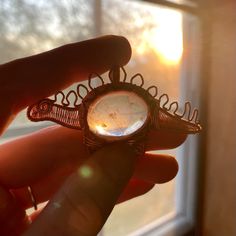 a person holding a ring in their hand with the sun shining through it's window