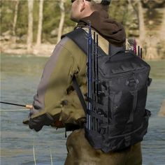 a man standing in the water while holding a fishing rod and wearing a backpack that is attached to his back