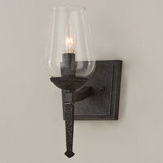 a light that is on the wall next to a glass vase with a candle in it