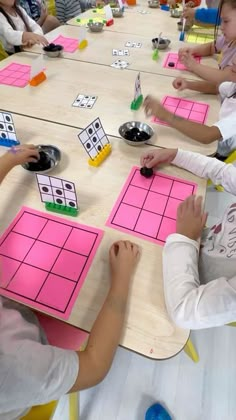 children are sitting at a table playing with pink squares