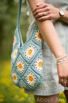 a woman is holding a crocheted bag in her hands and wearing bracelets