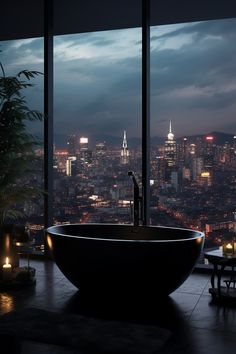 a large bathtub in front of a window overlooking the city lights at night time