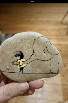 a person holding a rock with an elephant painted on it