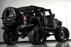 a black jeep is parked in a room with white walls and flooring on the wall