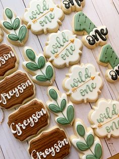 some decorated cookies are sitting on a white wooden table with green and brown decorations around them