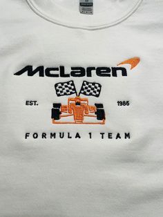 a white t - shirt with an orange and black racing car on it's chest