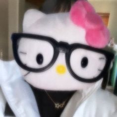 a stuffed animal with glasses and a pink bow on it's head in a room