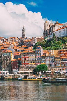 there are many boats in the water next to some buildings and trees on the hill