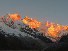 the mountains are covered in snow at sunset