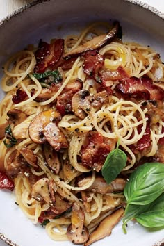 pasta with mushrooms, bacon and spinach in a white bowl