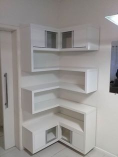 an empty corner in the middle of a room with white shelves and cupboards on each side