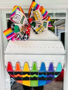 a door hanger decorated with colorful crayons and a large bow on it