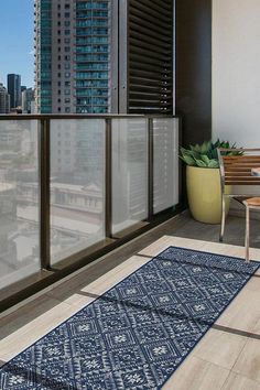 a balcony with a table, chair and potted plant next to the cityscape