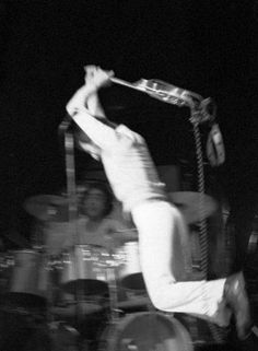 a man is jumping in the air with his hands up to his head as he plays drums