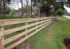 a wooden fence in the grass next to a road