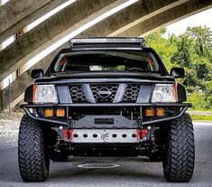 the front end of a black truck parked under an overpass