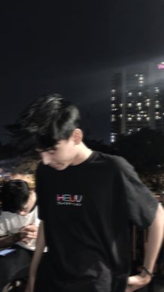 a young man standing on top of a roof next to a tall building at night