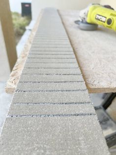 a close up of a table with a power tool on top of it and some sand in the background