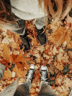 two people standing in leaves with their feet on the ground