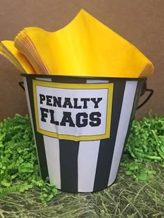 a black and white striped bucket with yellow napkins in it that says penalty flags