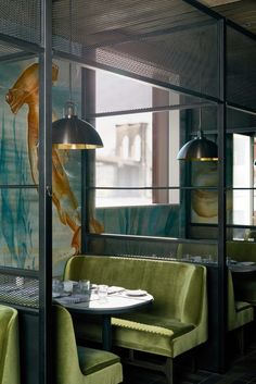 the interior of a restaurant with green velvet booths and gold fish paintings on the wall