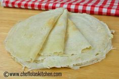 three tortillas sitting on top of a wooden table next to a red and white checkered napkin