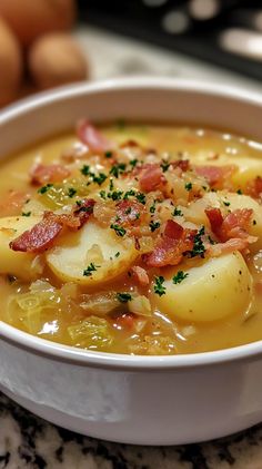 a bowl of soup with potatoes and bacon in it on a marble countertop next to eggs